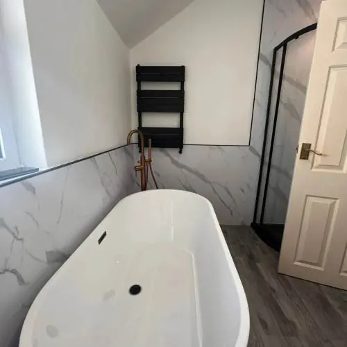 Freestanding bath and black towel radiator in a Cardiff loft bathroom
