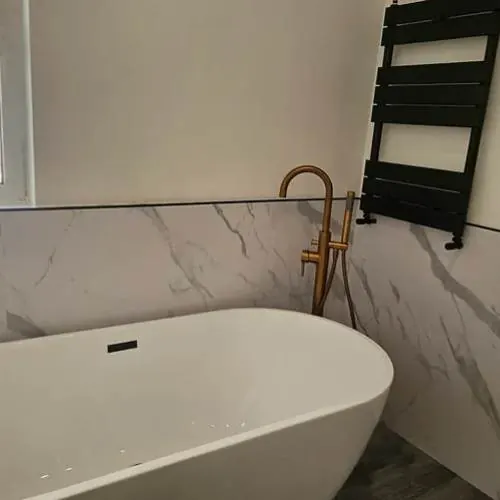 Freestanding bath with floor-standing tap and black towel radiator in Cardiff