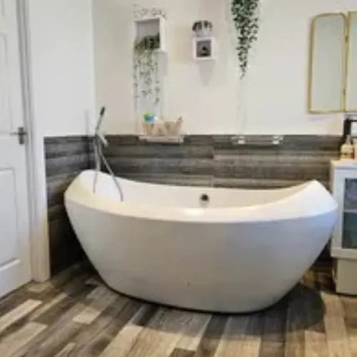 Freestanding bath on a wood-effect floor in a renovated Cardiff bathroom