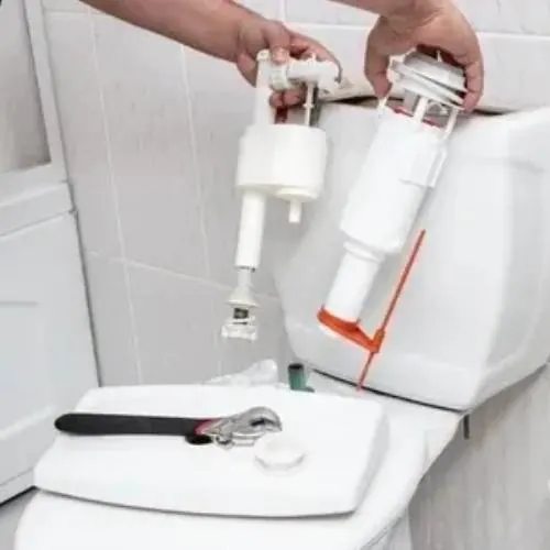 Plumber replacing a toilet cistern fill valve during a repair in Cardiff