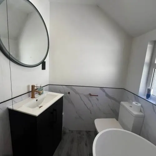 Black vanity unit, round mirror and toilet installed in a Cardiff bathroom