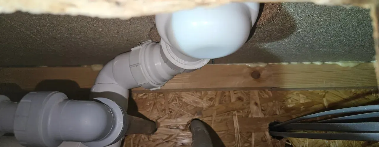 Plumber in Roath fitting new white waste pipework under a bath